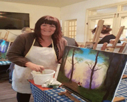 Happy students showing their finished Bob Ross landscape paintings at oil painting class in Kent