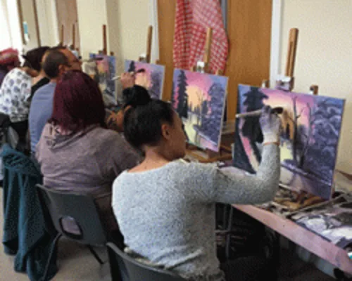 Student holding finished Bob Ross style winter landscape oil painting at class in Kent