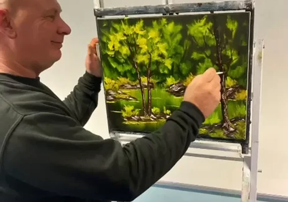 Mark Terrell painting a green Bob Ross forest landscape on canvas at a Kent painting class