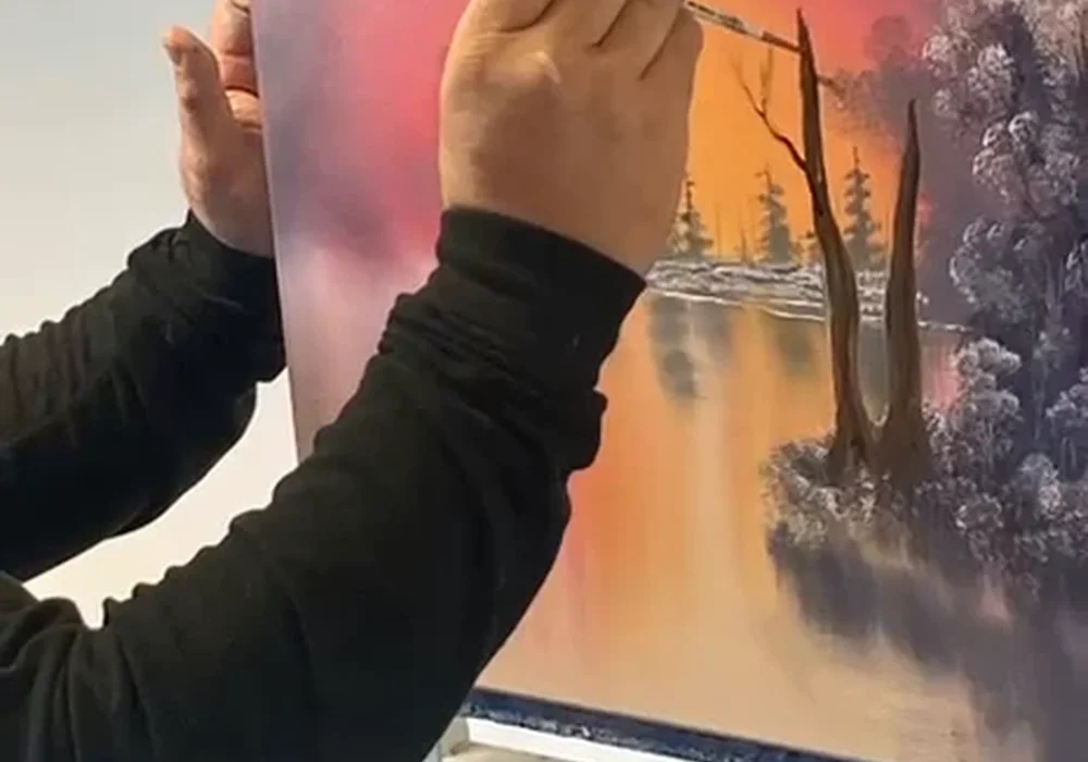 Mark Terrell painting a Bob Ross sunset with trees and water reflections in oils