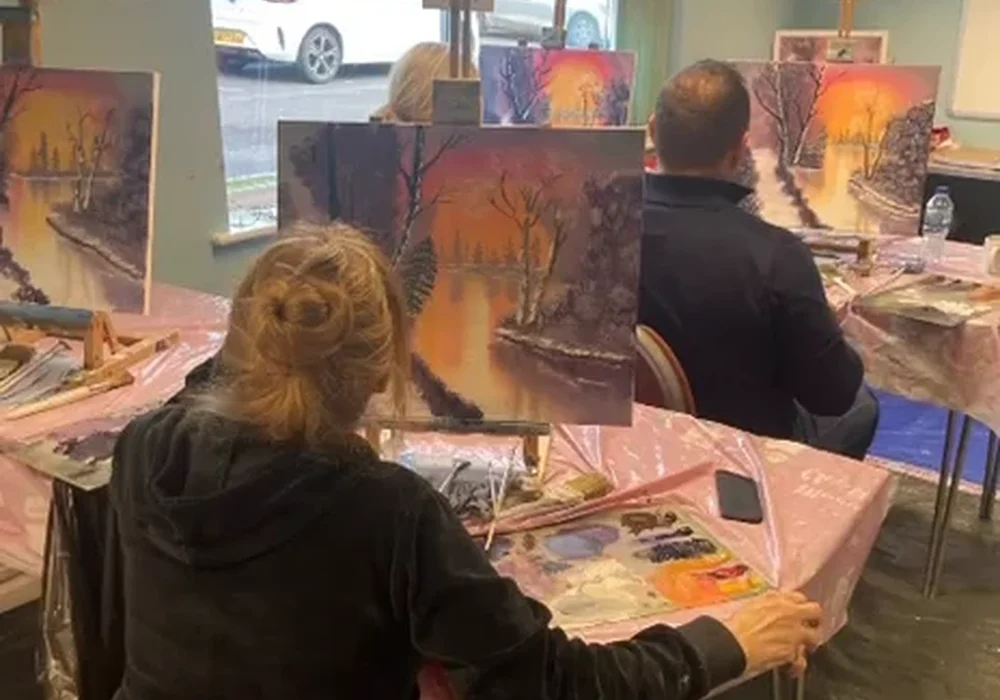 Beginner student painting a Bob Ross autumn landscape at an oil painting class in Kent