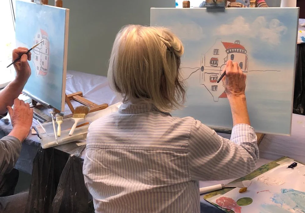 Student painting a lighthouse with water reflection at a beginner oil painting class in Kent