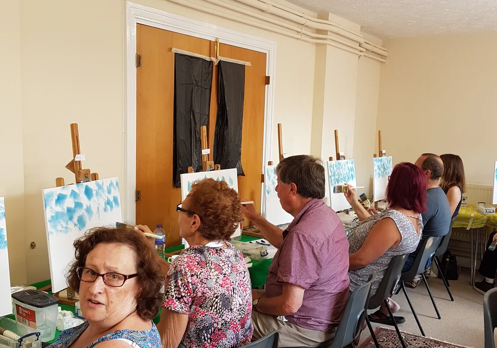 Smiling students enjoying a relaxed Bob Ross oil painting class in Kent