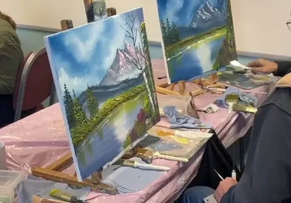 Students painting Bob Ross mountain lake landscapes at a one-day oil painting class in Whitstable